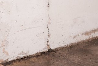 Rissige Wand mit dunklen Ablagerungen am Boden